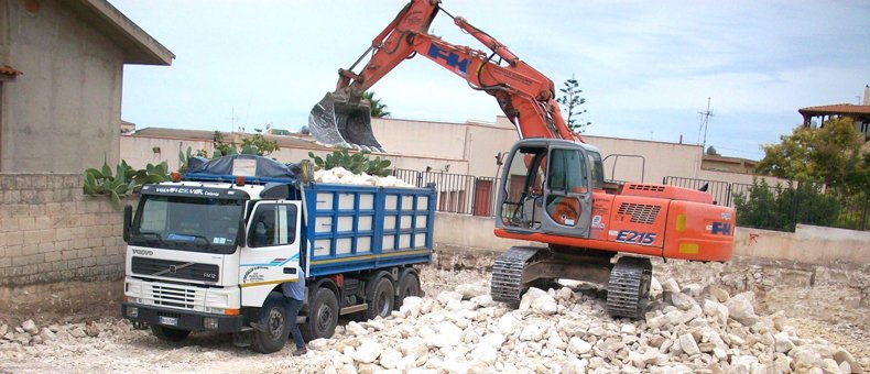 escavatore cingolato hitachi che carica su cassone camion dei calcinacci